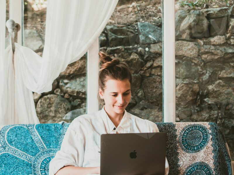 Mujer sentada escribiendo en laptop